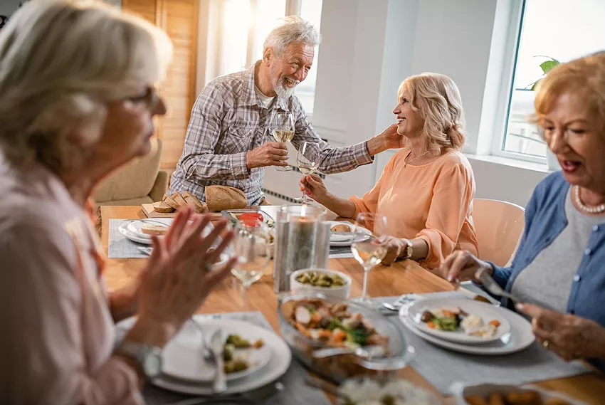  Repas convivial au restaurant des aînés de Mérindol, où des personnes âgées partagent un repas maison dans une ambiance chaleureuse, avec un service de navette disponible pour faciliter leurs déplacements. 